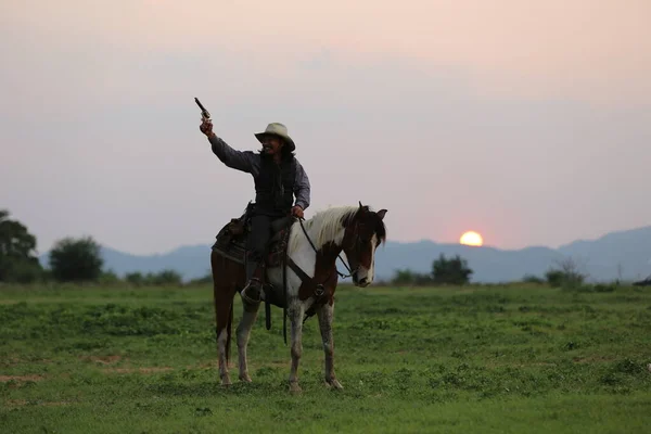 牛仔骑着马 手拿着枪挡住日落 — 图库照片