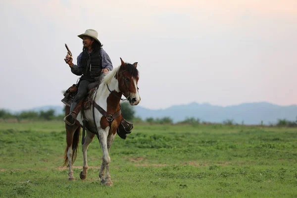 Kovboj Koni Rukou Drží Zbraň Proti Západu Slunce — Stock fotografie