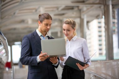 İş adamı ve iş kadını ofis dışında yürürken iş tartışıyorlar