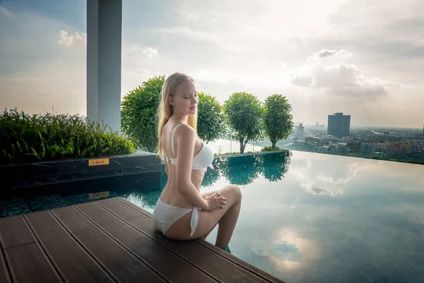 年轻女子享受阳光 瘦小女子模特儿穿着白色比基尼在游泳池边 — 图库照片