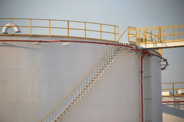 large Industrial tanks for petrol and oil with blue sky.Fuel tanks at the tank farm. metal stairs on the side of an industrial oil container.Staircase on big fuel tank