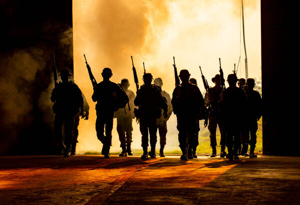 Силуэты армейских солдат в тумане на закате, морские пехотинцы в действии, окруженные огнем и дымом, стреляющие из автомата и пулемёта, атакующие врага