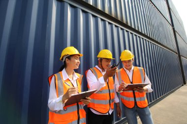 Mühendis ya da denetleyici limandaki kargo kutusunu kontrol ediyor ve kontrol ediyor. Foreman endüstrideki endüstriyel yük gemisini kontrol ediyor. Ulaştırma ve lojistik konsept. 