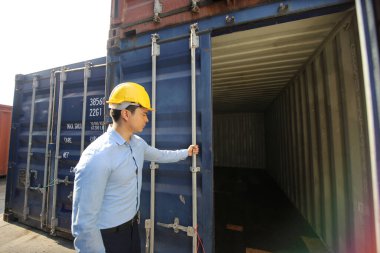 Mühendis ya da denetleyici limandaki kargo kutusunu kontrol ediyor ve kontrol ediyor. Foreman endüstrideki endüstriyel yük gemisini kontrol ediyor. Ulaştırma ve lojistik konsept. 