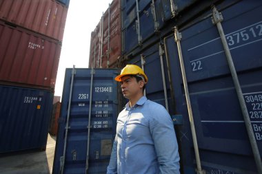 Mühendis ya da denetleyici limandaki kargo kutusunu kontrol ediyor ve kontrol ediyor. Foreman endüstrideki endüstriyel yük gemisini kontrol ediyor. Ulaştırma ve lojistik konsept. 