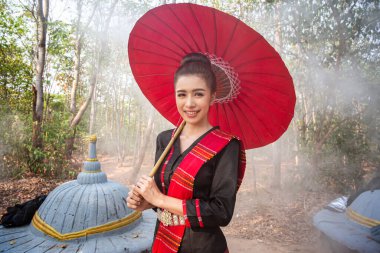 Portrait Of Smiling Woman with red umbrella Standing  In forest of Thailand. clipart