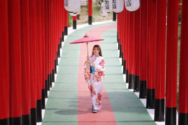  Kimonolu bir kadın Japon bahçesindeki tapınağa doğru yürüyor..