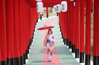 Kimonolu bir kadın Japon bahçesindeki tapınağa doğru yürüyor..