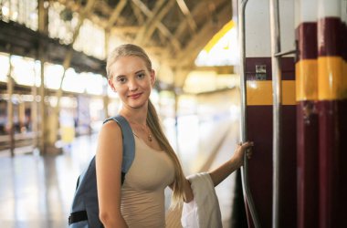 Trende bekleyen genç bir kadın, Bangkok, Tayland 'daki tren istasyonunda rahat ve kaygısız bir şekilde trene binmeden önce. Seyahat fotoğrafçılığı. Yaşam biçimi.