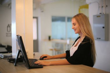 İş yerinde dizüstü bilgisayar kullanan gülümseyen bir kadın, izleyici çekmek ve içerik yaratmak isteyen küçük işletmeler için iş yerinde yeni pazarlama teknolojisi benimseyebilir. Serbest Çalışan Konsepti.