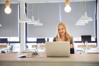 İş yerinde dizüstü bilgisayar kullanan gülümseyen bir kadın, izleyici çekmek ve içerik yaratmak isteyen küçük işletmeler için iş yerinde yeni pazarlama teknolojisi benimseyebilir. Serbest Çalışan Konsepti.