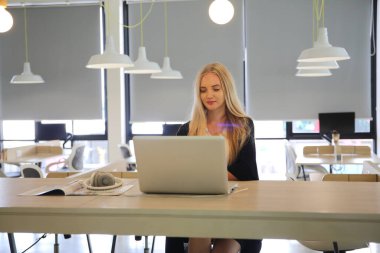 İş yerinde dizüstü bilgisayar kullanan gülümseyen bir kadın, izleyici çekmek ve içerik yaratmak isteyen küçük işletmeler için iş yerinde yeni pazarlama teknolojisi benimseyebilir. Serbest Çalışan Konsepti.