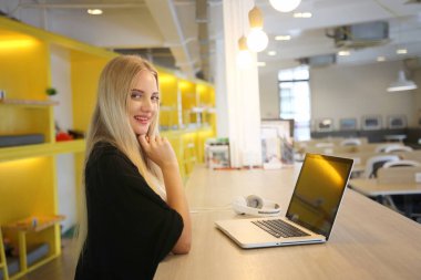 İş yerinde dizüstü bilgisayar kullanan gülümseyen bir kadın, izleyici çekmek ve içerik yaratmak isteyen küçük işletmeler için iş yerinde yeni pazarlama teknolojisi benimseyebilir. Serbest Çalışan Konsepti.