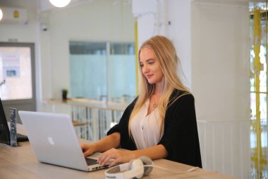 İş yerinde dizüstü bilgisayar kullanan gülümseyen bir kadın, izleyici çekmek ve içerik yaratmak isteyen küçük işletmeler için iş yerinde yeni pazarlama teknolojisi benimseyebilir. Serbest Çalışan Konsepti.