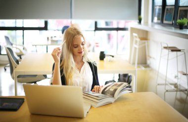 İş yerinde dizüstü bilgisayar kullanan gülümseyen bir kadın, izleyici çekmek ve içerik yaratmak isteyen küçük işletmeler için iş yerinde yeni pazarlama teknolojisi benimseyebilir. Serbest Çalışan Konsepti.