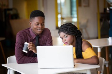 Kahve molası sırasında bir kafede dizüstü bilgisayarda çalışan Afrikalı genç bir kızın portresi. Mola, rahatla.