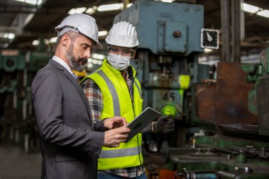 Mühendis müdürü ve Fabrika İşçi Takımı üretim hattında kontrol makinesi. Takım çalışması konsepti.