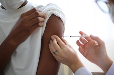 Doktor hastaya aşı yapıyor, grip aşısı. Doktor hastanın omzunda aşı yapıyor.