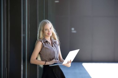 Modern bir ofiste dizüstü bilgisayarda çalışan bir iş kadını.