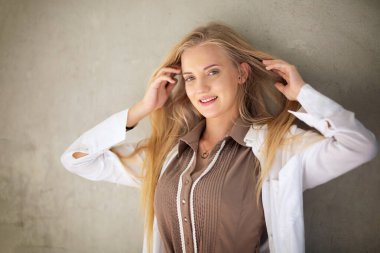 Güzel bir kadın portresi. Sarı saçlar. Duvarda duruyor.