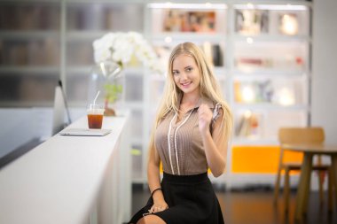 Bilgisayarla çalışan güzel genç bir kadın konsantre olmuş ve gülümsüyor.