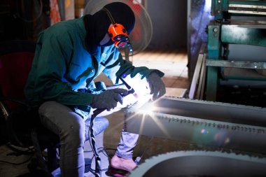 Kaynak ustası, fabrikada kıvılcımlı çelik üzerine çelik öğütücü, endüstriyel atölyede kaynak işlemi, çerçeveli aletli eller kullanırdı..