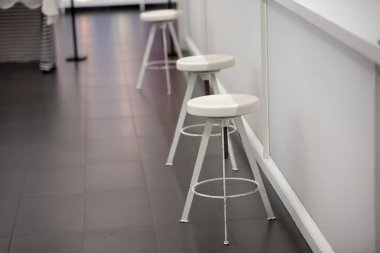 Tezgahta üç beyaz sandalye.