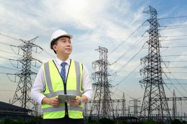 Teftiş mühendisi, sanayi bölgesinde yüksek elektrik gücüne karşı tablet bilgisayarı tutuyor..