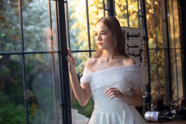 Gelinlik giymiş, saçları kıvırcık, güzel, çekici, gülümseyen bir kadın resmi..