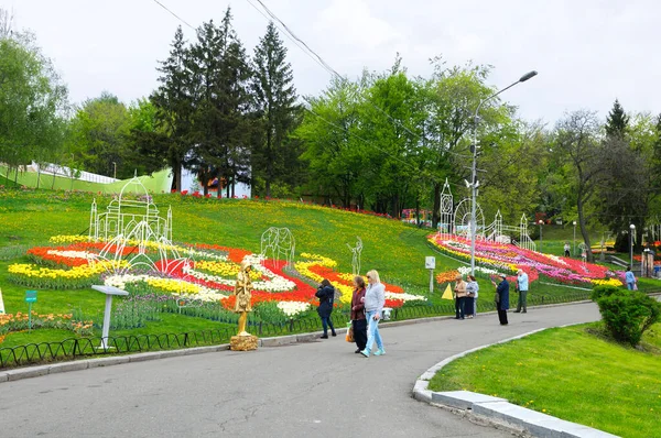 Besucher gehen durch den Park und betrachten helle Tulpen, die auf einer Liegewiese gepflanzt wurden — Stockfoto