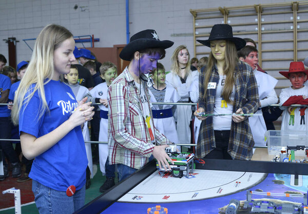 Young people adjusting robot before launching it. School tournament among pupils. January 9, 2019. Kiev, Ukraine