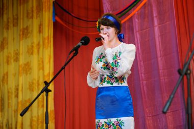 Ukrayna yerlisi kostümlü bir kız köy konağının sahnesinde şarkı söylüyor. 12 Ağustos 2019. Krupichpole, Chernigivska oblast, Ukrayna