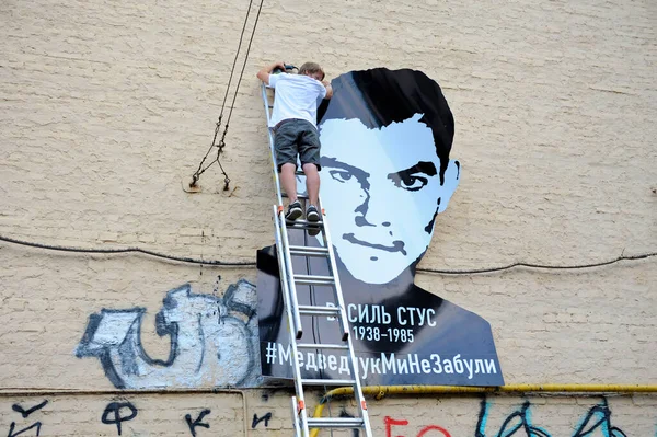 Genç eylemci, ünlü Ukraynalı şair ve muhalif Vasyl Stus 'un poster portresini binanın duvarına astı. 12 Haziran 2018. Kyiv, Ukrayna