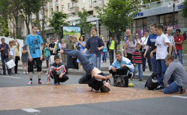 Genç bir çocuk, sokak dansçısı, kaldırımda dans gösterisi, yanında izleyen gençler. 21 Mayıs 2012. Kiev, Ukrayna