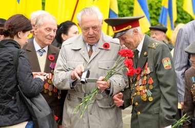 Gaziler, Büyük Vatanseverlik Savaşı 'nın yaşlı bir adamı Zafer Günü' nde elinde çiçeklerle kamerayı izliyor. 9 Mayıs 2018. Kiev, Ukrayna