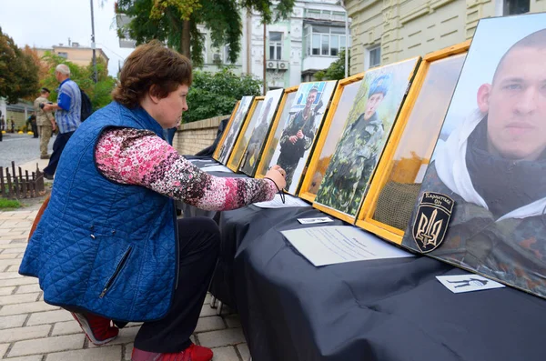 Anma Duvarı 'nın önünde elinde asker portreleri ve yas tutan bir kadın. Rusya 'daki Ukrayna savaşında ölen Ukrayna askerleri için Anma Günü. 29 Ağustos 2018. Kiev, Ukrayna