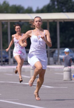 Sıradan elbiseli ve yüksek topuklu ayakkabılı kızlar bahis için sokakta koşuşturuyor. 3 Temmuz 2013. Kiev, Ukrayna