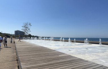 Deniz kenarındaki gezinti güvertesi Nea Paralia, Thermaic Gulf, çalışan insanlar. 10 Ağustos 2025. Selanik, Yunanistan