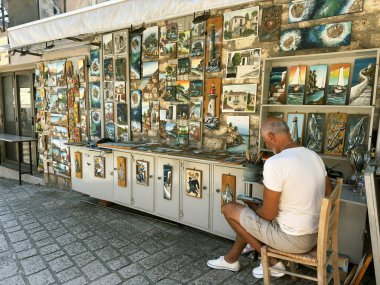 Hatıra ve resim dükkanı, kendi çizdiği resimleri satan ressam. Afytos veya Athitos, Yunanistan 'ın Chalkidiki adasındaki küçük bir köy tatil köyü. 10 Ağustos 2025. Afytos, Yunanistan