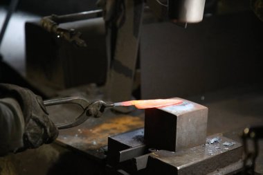 Isıtılmış malzemeleri çekiçle şekillendiren bir zanaatkar..