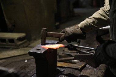 Isıtılmış malzemeleri çekiçle şekillendiren bir zanaatkar..
