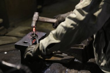 Isıtılmış malzemeleri çekiçle şekillendiren bir zanaatkar..