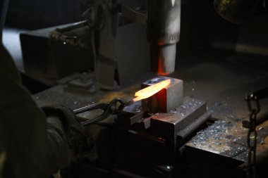 Isıtılmış malzemeleri çekiçle şekillendiren bir zanaatkar..