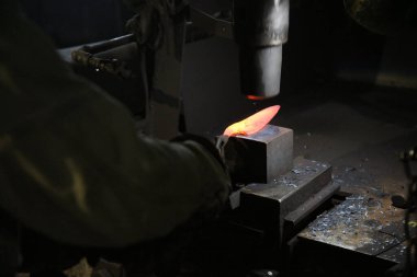 Isıtılmış malzemeleri çekiçle şekillendiren bir zanaatkar..