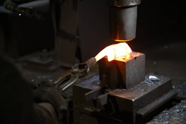 Isıtılmış malzemeleri çekiçle şekillendiren bir zanaatkar..