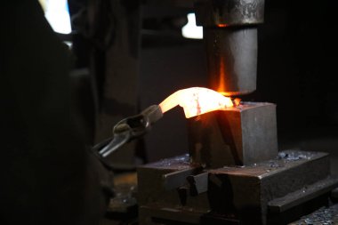 Isıtılmış malzemeleri çekiçle şekillendiren bir zanaatkar..