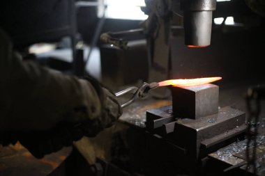 Isıtılmış malzemeleri çekiçle şekillendiren bir zanaatkar..