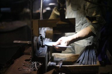 Bir zanaatkar, kumaşı bıçak şeklinde kesmek için el makasıyla keser.