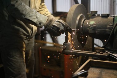 Metali öğütücüyle şekillendiren bir zanaatkar.