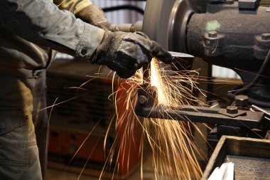 Metali öğütücüyle şekillendiren bir zanaatkar.